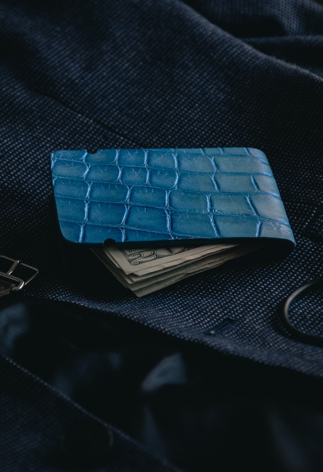 blue wallet with cash laying on suit